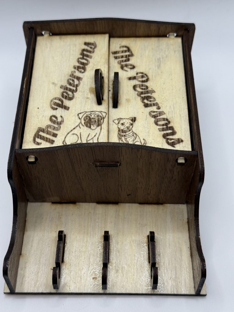 Custom handmade gift, maple and walnut laser-cut wooden key holder with engraved design, handcrafted wall organizer for keys and small accessories.
