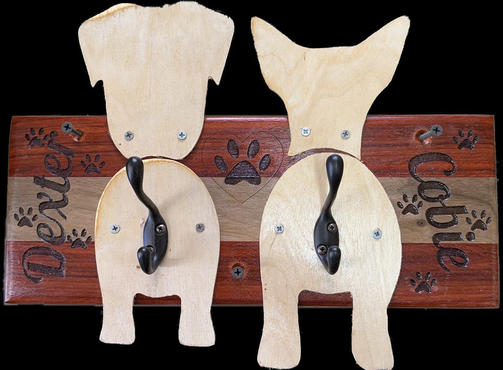 Custom hardwood dog leash holder sign made from padauk and cherry with basswood dog silhouettes and engraved names, handcrafted wall display by 3 Dogs Woodworking.