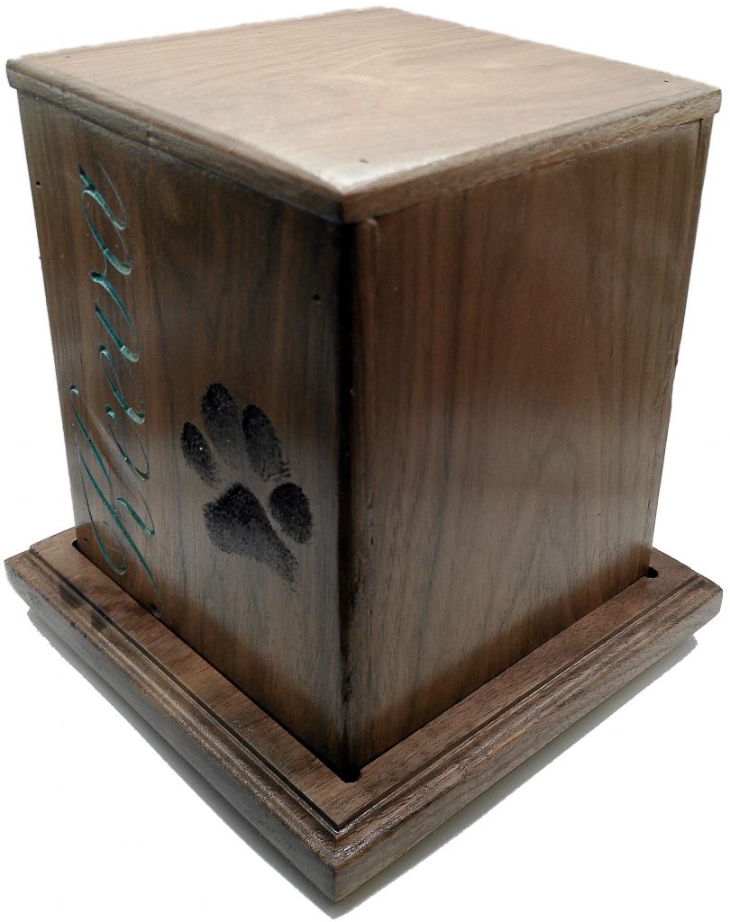 Front right view of Keeva's handcrafted walnut custom dog memorial urn featuring turquoise engraved lettering, life-size paw print, and sculpted base.