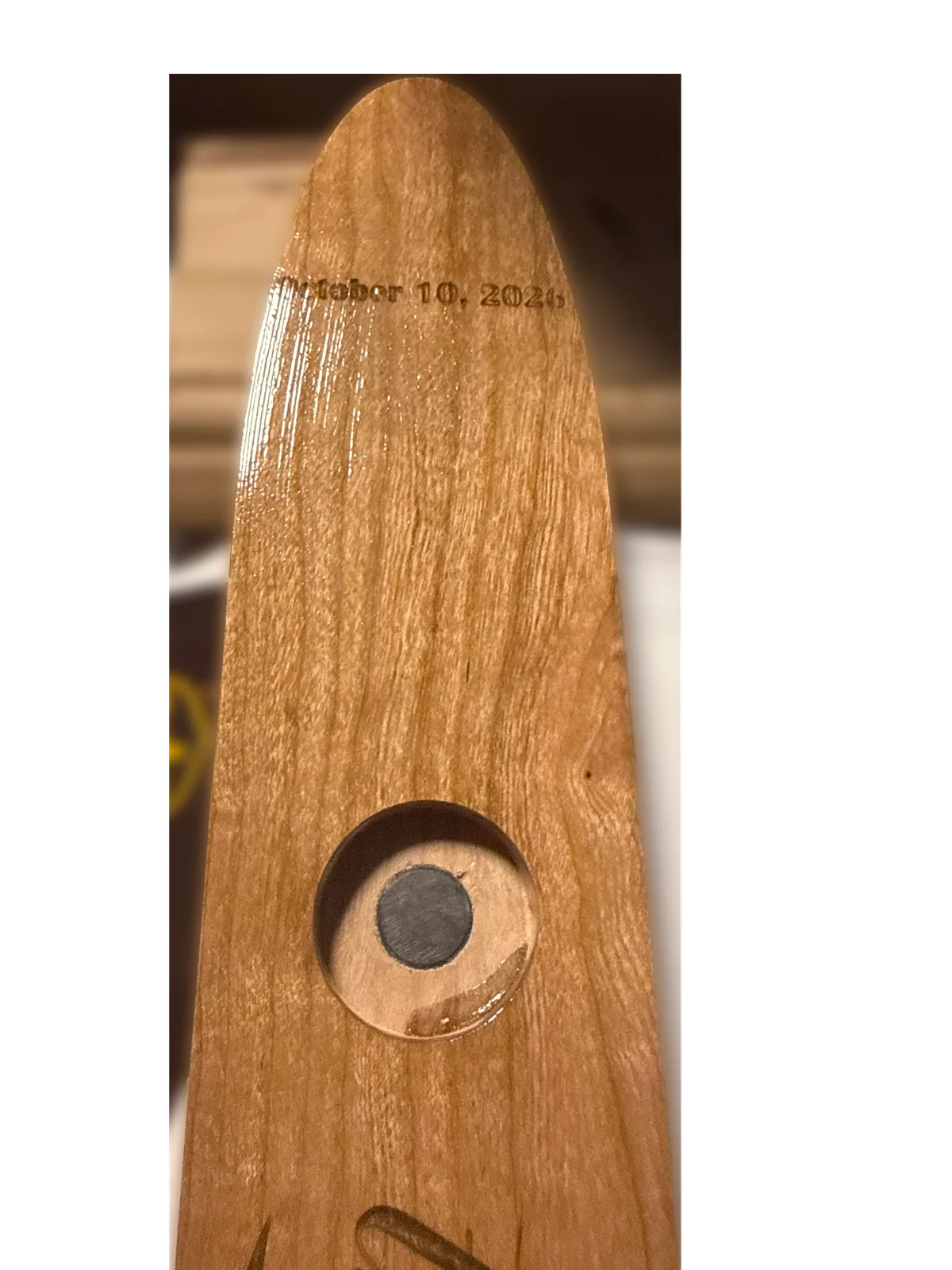 Close view of a magnetic shot glass position and engraved date on the cherry shotski